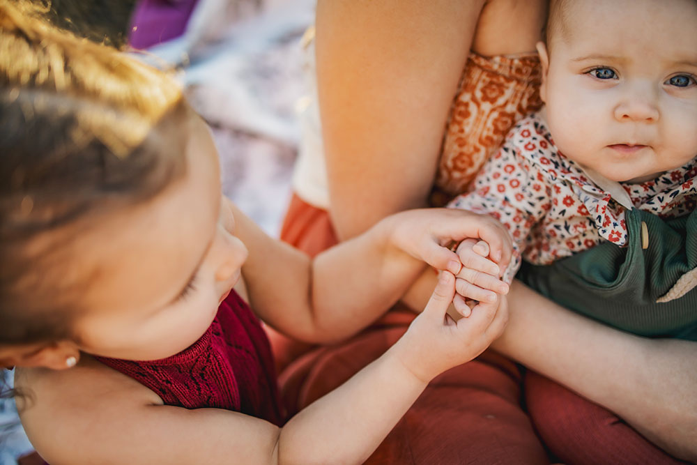 toddler holds baby sister's hand in Mckinney Texas at Erwinn Park.