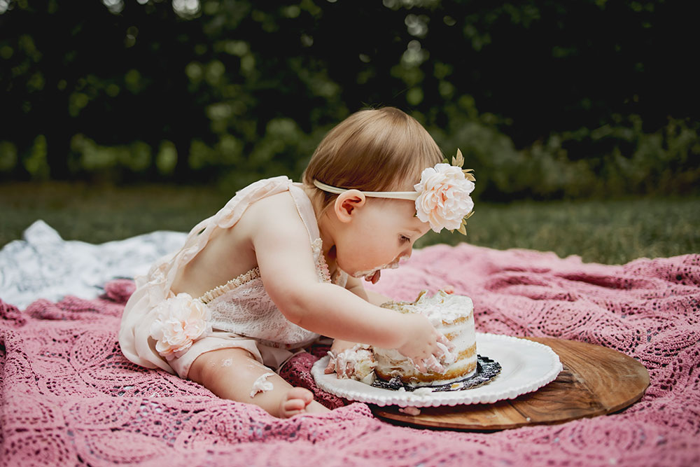 A baby girl's first birthday is celebrated with a cake smash session