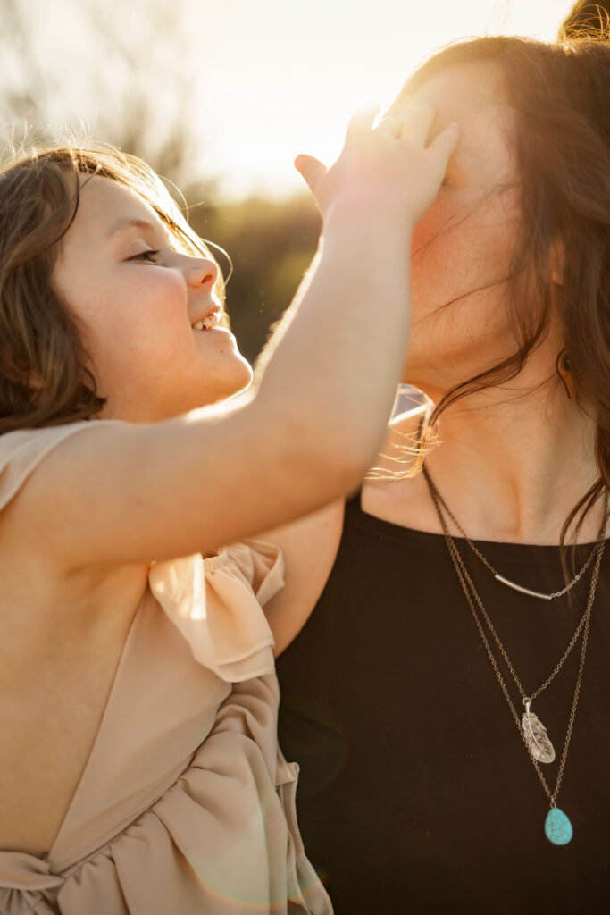 A little girl plays with her mom in the sunshine at a photo session at Lake Grapevine with Anna Roorda Photography.