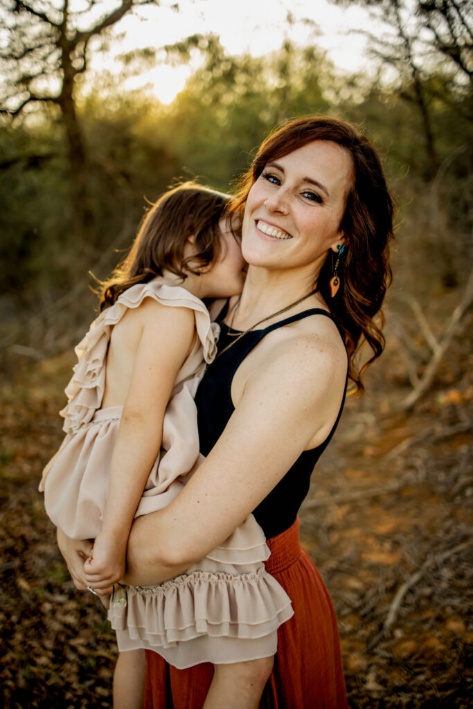 A mom holds daughter in the sunshine at a spring photo session at Lake Grapevine with Anna Roorda Photography.