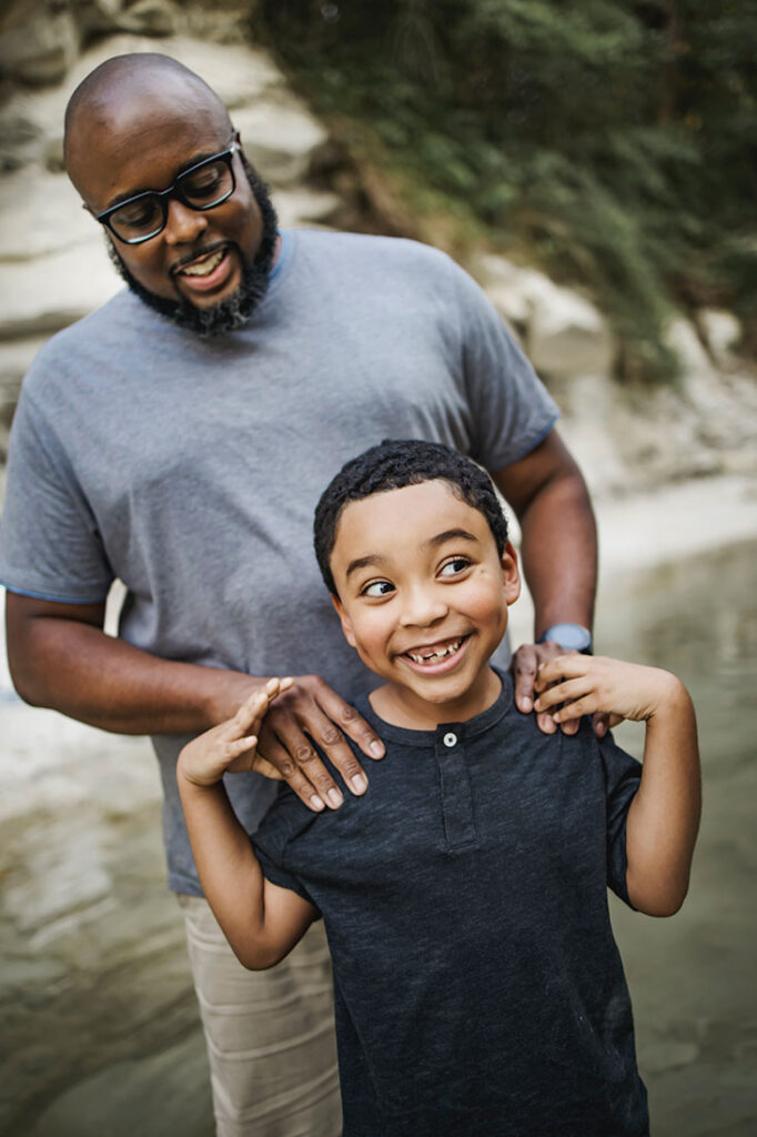 Young boy from Little Elm, TX laughs with his dad while at a session in Frisco Texas with photographer, Anna Roorda