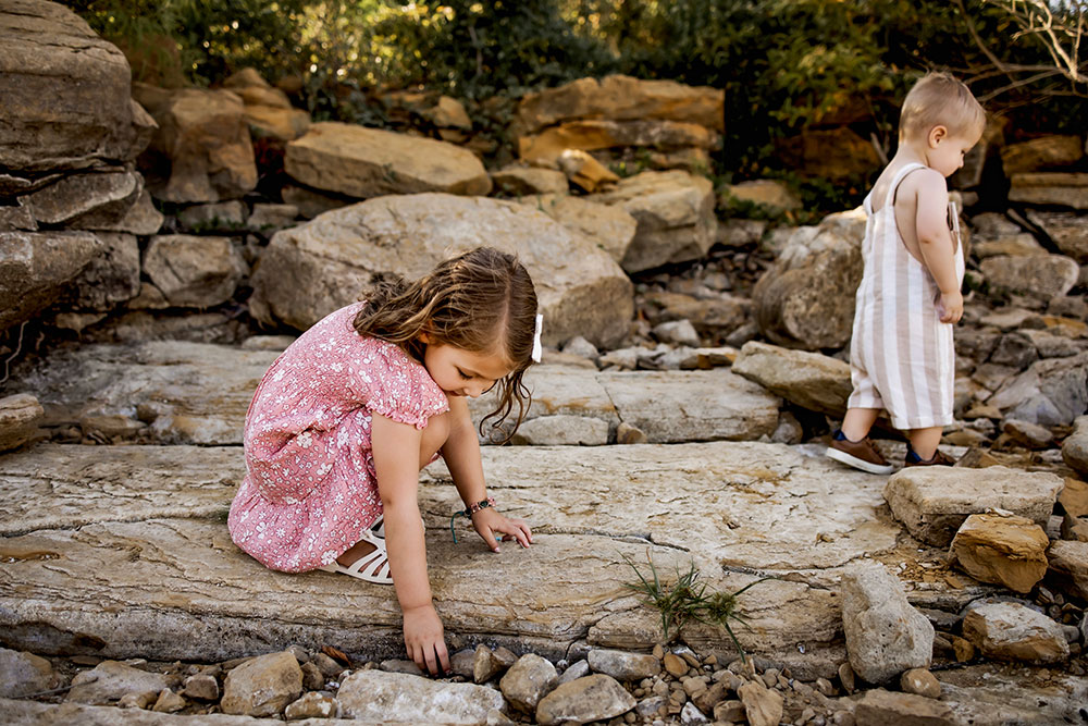 A young girl explores the rocky shores of Grapevine lake at a family photography session in Grapevine Texas.
