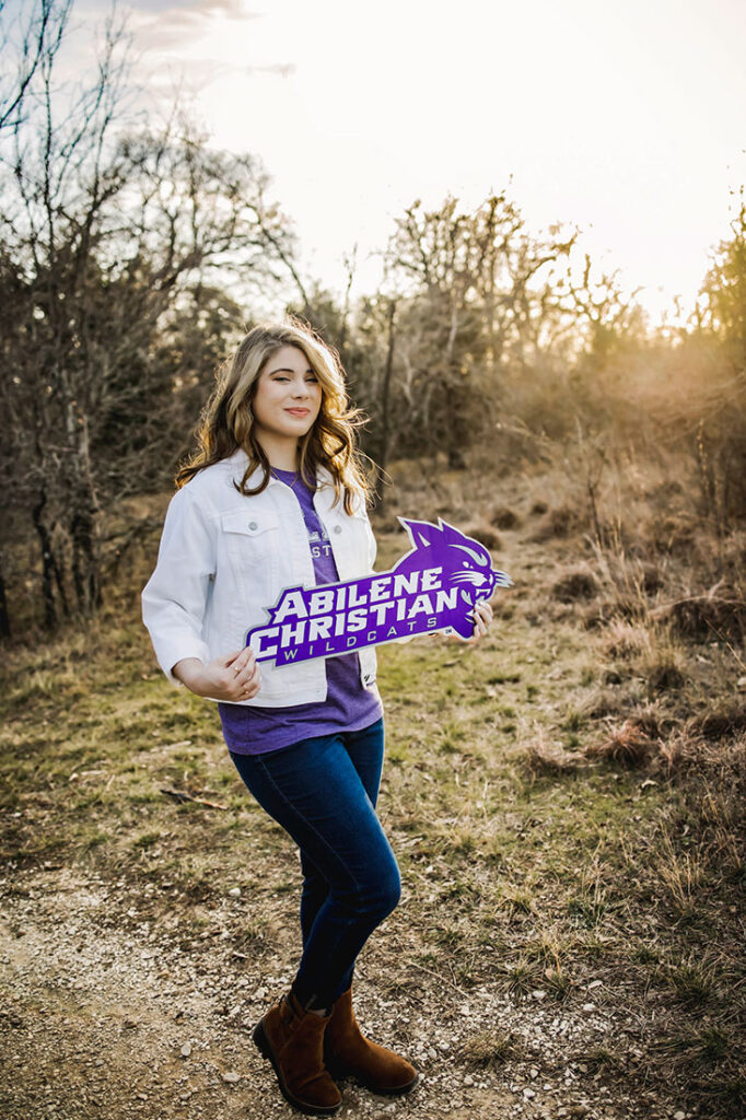 A senior girl from Plano Texas poses with her college acceptance banner from Abilene Christian University.