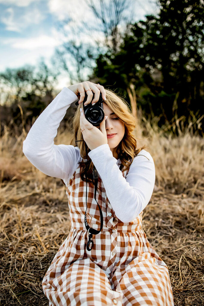 Senior student who enjoys photography poses with her camera in Flower mound, TX