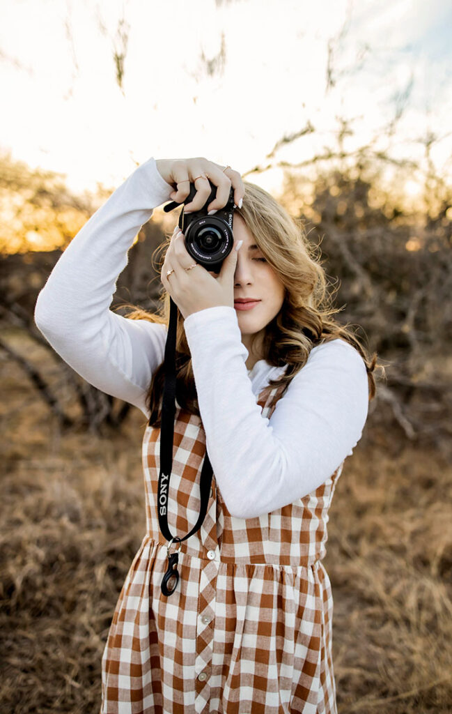 A senior girl from Plano Texas poses with her camera, showing off her love of photography.