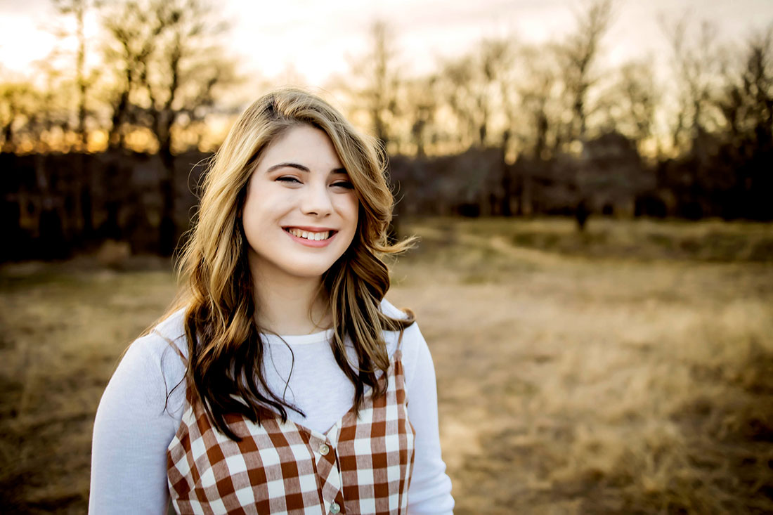 Senior girl from Plano Texas smiles for the camera during golden hour.