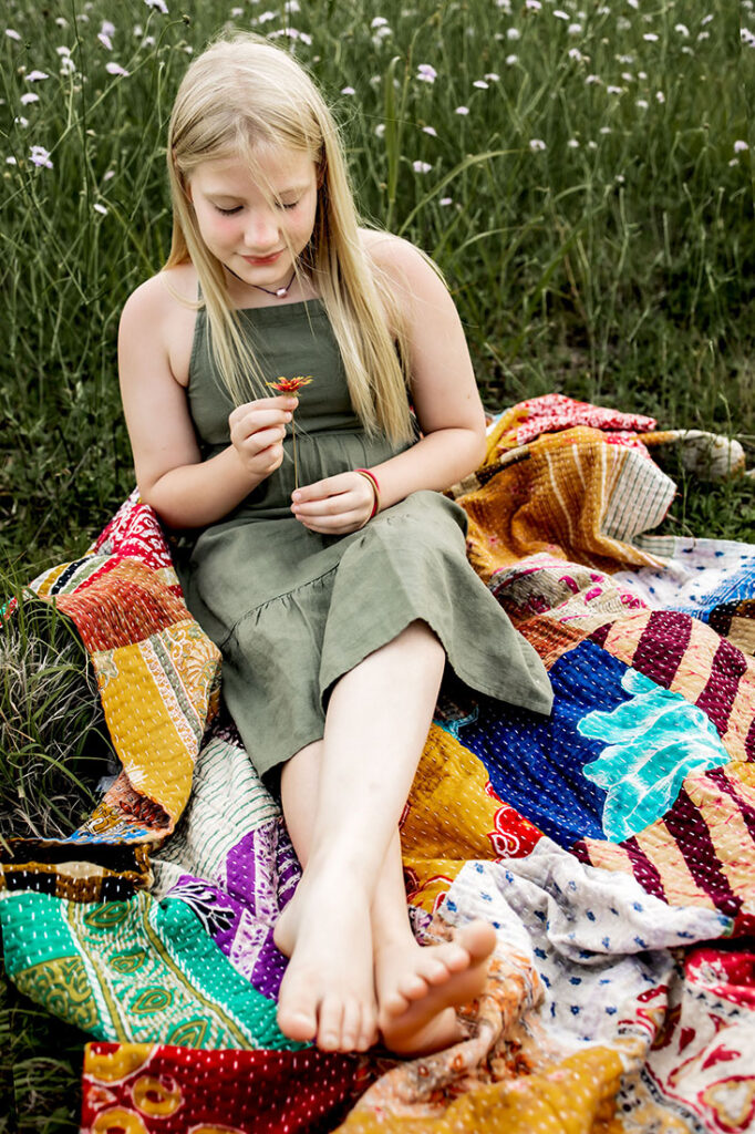 Young girl sits in a field of wild flowers in Plano, TX at Arbor Hills Nature Preserve.