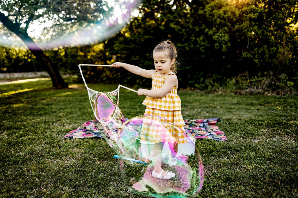Five year old girl from Southlake plays with giant bubbles at Liberty Park.