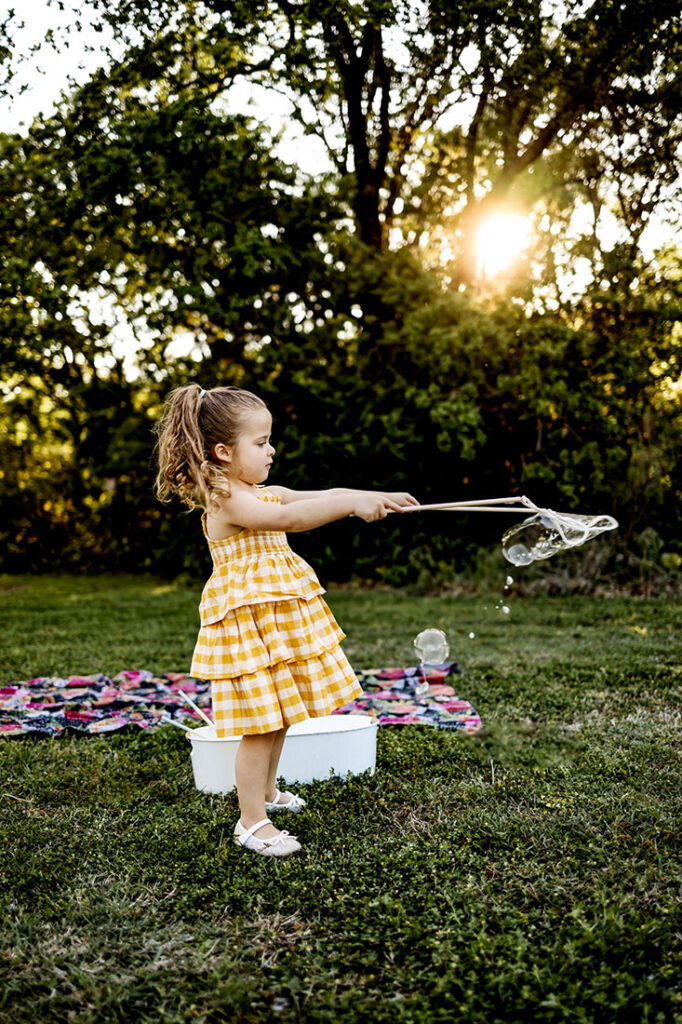 Five year old girl plays with giant bubbles in the Spring at Liberty Park in Southlake , TX.