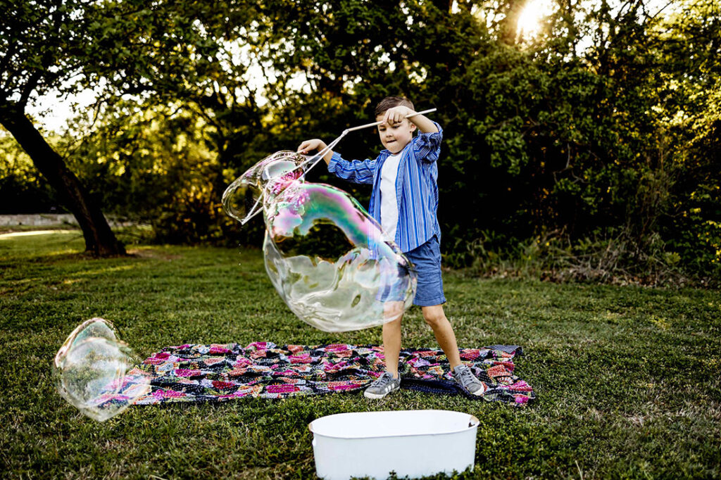Nine year boy plays with giant bubbles in the Spring at Liberty Park in Southlake , TX.