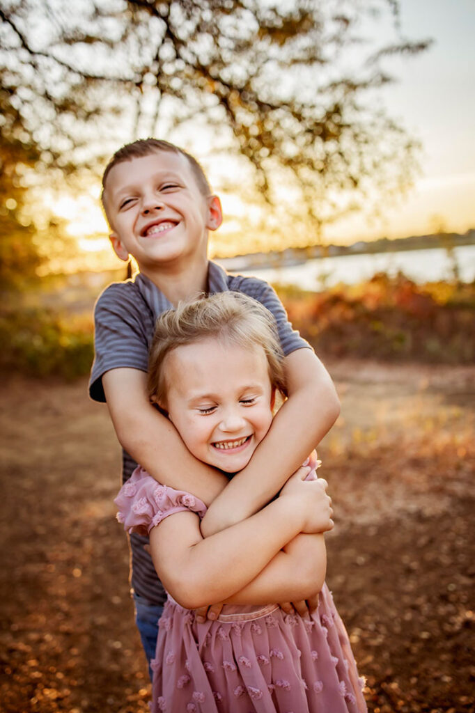 A brother and sister laugh and hug at a session in Grapevine at Lake Grapevine.