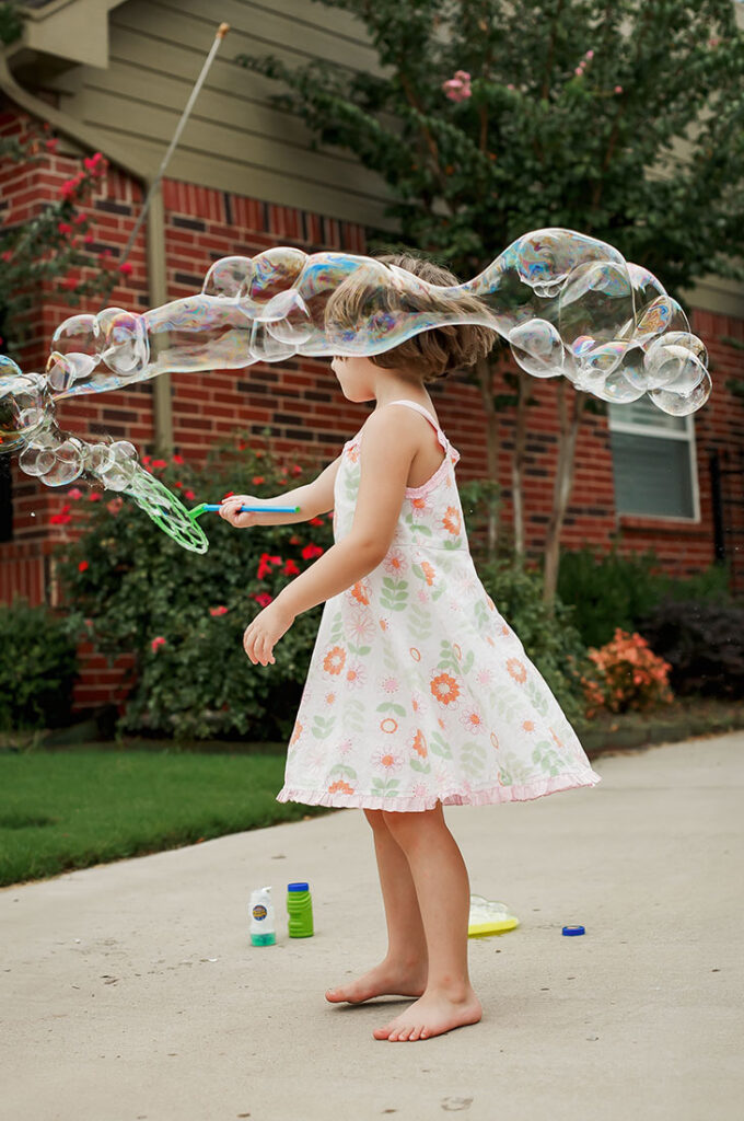 A girl at home in Castle Hills plays with a bubble wand.
