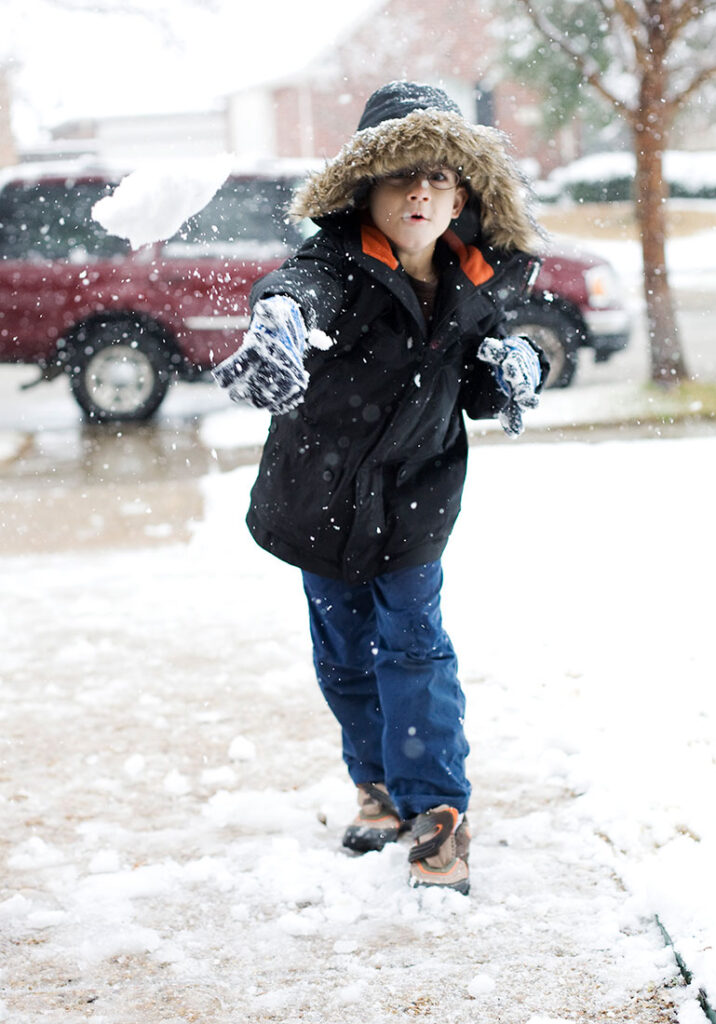 A boy throws a snowball at his home in Carrollton texas.