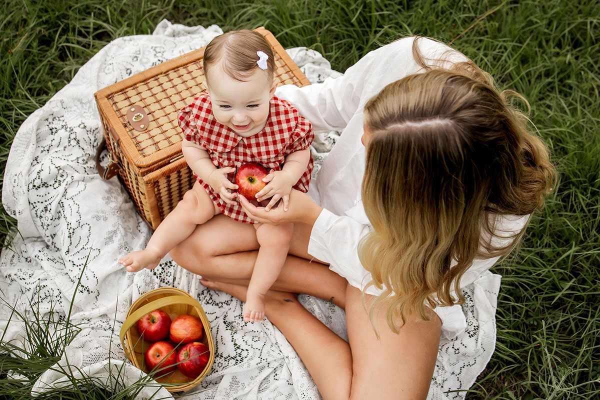A mom and her baby sitting in a field in Mckinney Texas at a summer photo session.