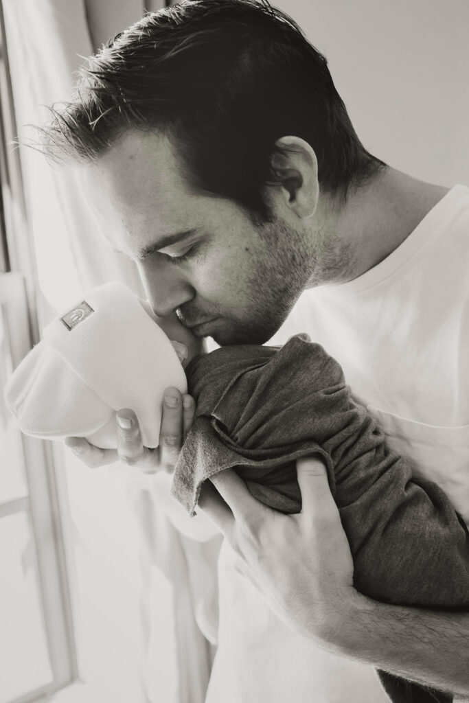 father holding his newborn son at an in home session in a Dallas, Texas home.