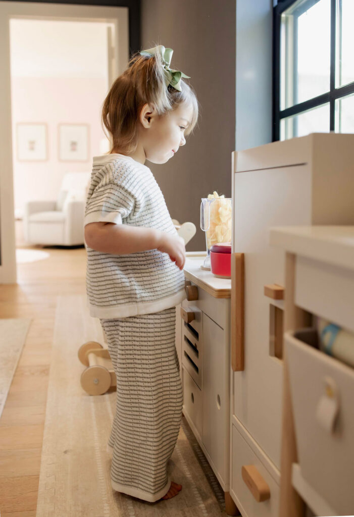A toddler plays in her play kitchen at an in home photo session