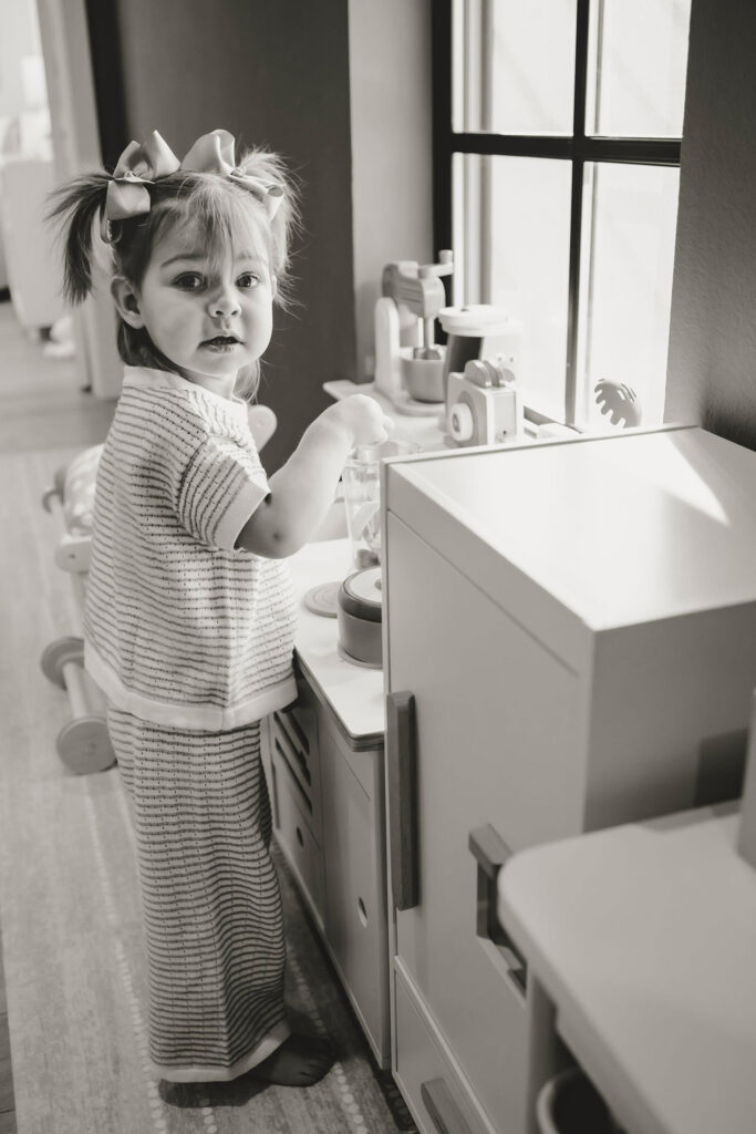 A toddler plays in with her toys at in in home session in Dallas Texas.